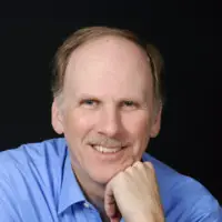 headshot of man in button up shirt with face resting on fist