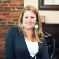headshot of female executive in dark suit with white blouse standing in office