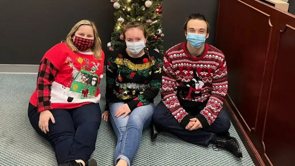Team members showcasing their ugly holiday sweaters
