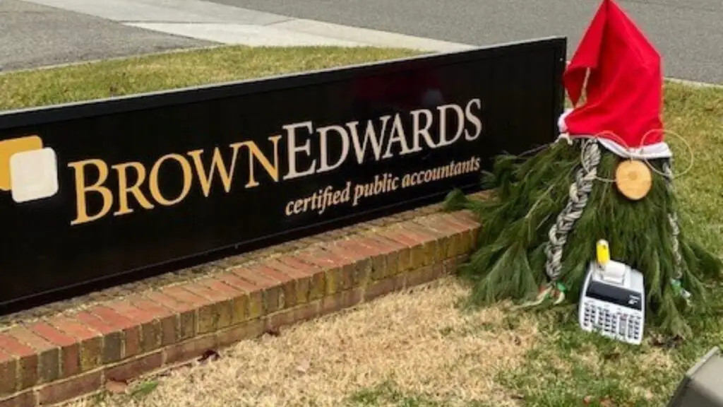 A gnome tree dressed as an accountant in front of the brown edwards office sign