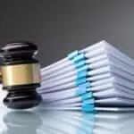 Court gavel with stack of papers on table
