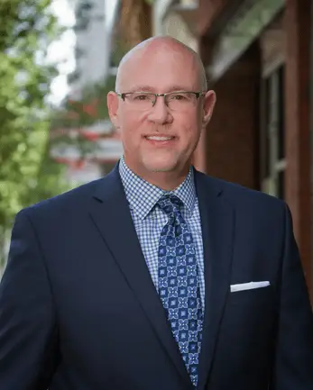 Headshot of many in blue suit and tie