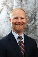 Headshot of man in blue suit with red and blue tie